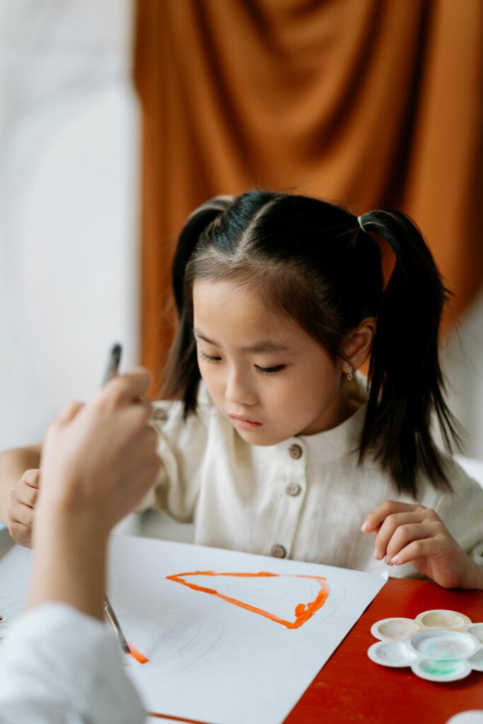 A few-year-old girl painting on a piece of paper.