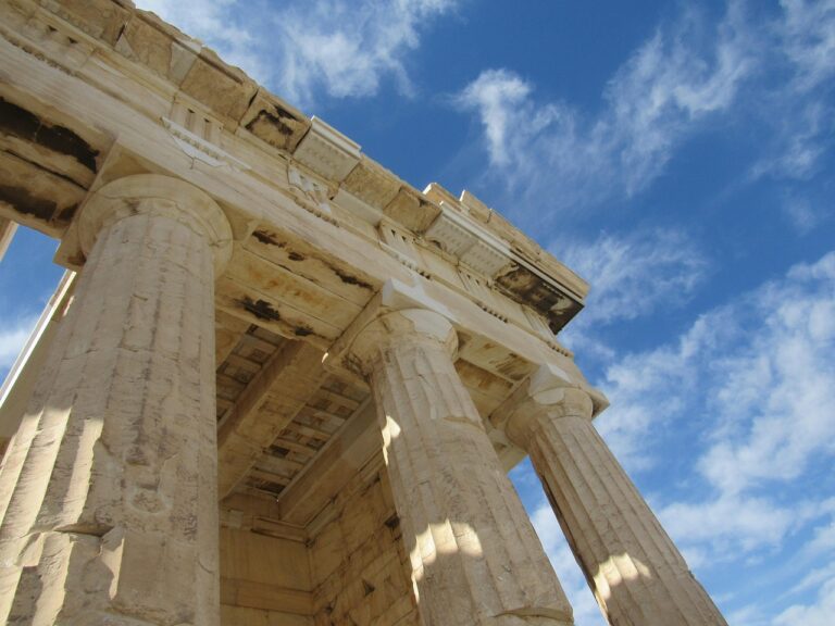 Fragment of an ancient building with columns against a blue sky with some clouds.