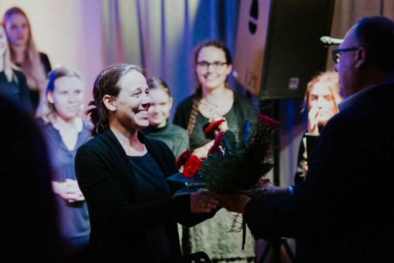 Smiling female receiving flowers on the stage.